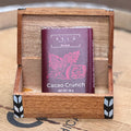 Xela Cacao Crunch chocolate bar in a wooden box on a wooden surface.